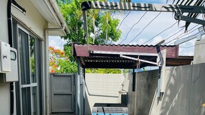 Un espacio al aire libre cubierto con un generador azul, una unidad de aire acondicionado blanca y una reja metálica.