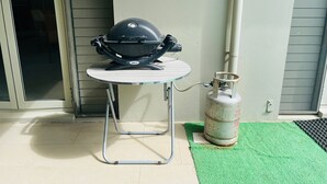 Una parrilla portátil sobre una mesa, con un tanque de propano a su lado.
