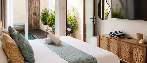 A hotel room with a bed, a TV, a wooden cabinet, and a view of the outdoors.