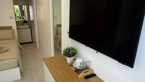 Uma sala de estar moderna com televis ão de tela plana na parede, uma mesa de console de madeira com um controle remoto e um pequeno vaso de planta.
