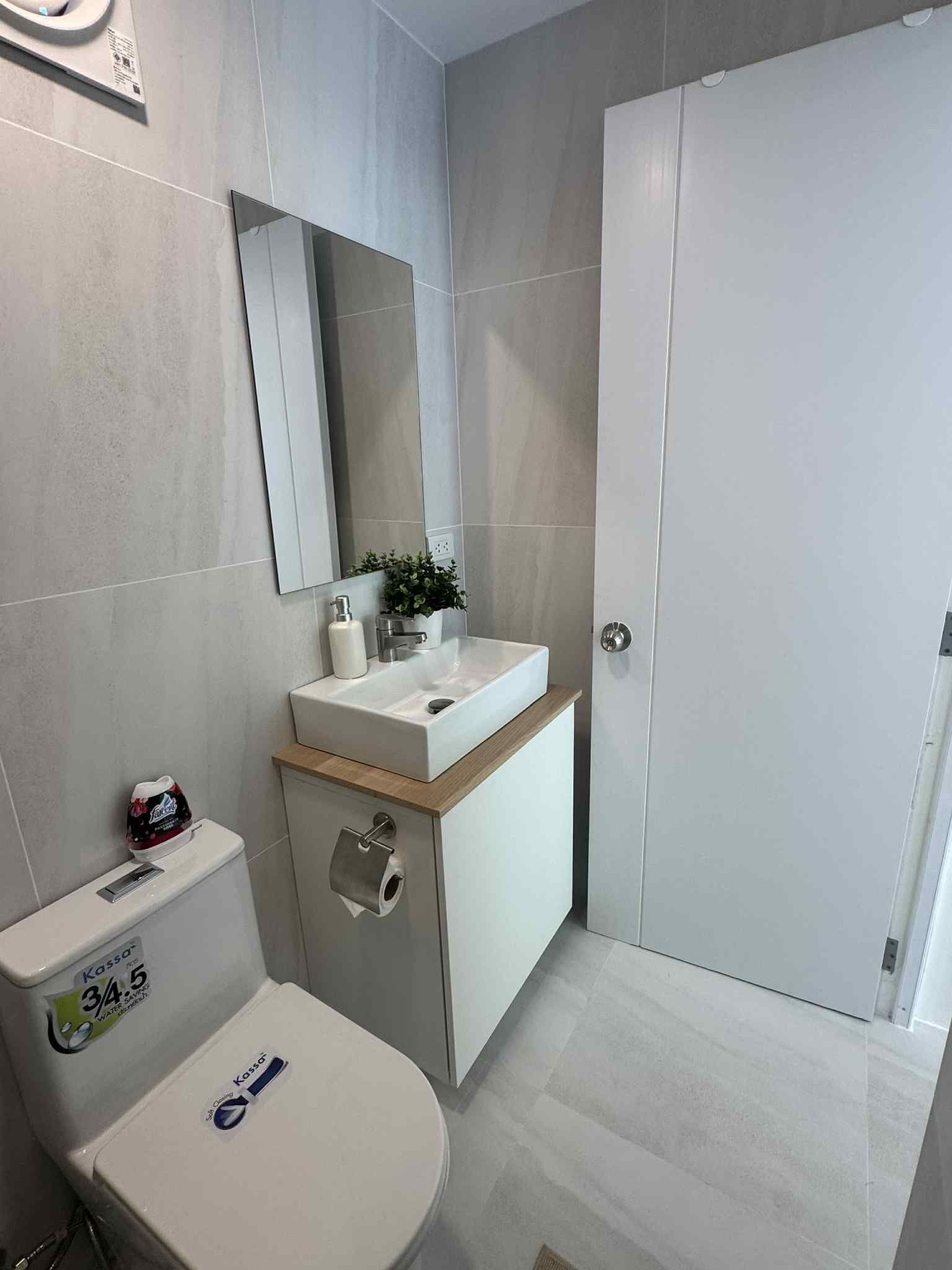 A modern bathroom with a toilet, sink, mirror, and a cabinet.
