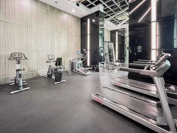 A modern gym with treadmills, weight machines, and a mirrored wall. - Senvin by Kozystay - Alam Sutera (South Tangerang)