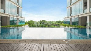 Ein modernes Hotel mit großzügigem Infinity-Pool, einer Holzterrasse und üppiger Bepflanzung im Hintergrund.