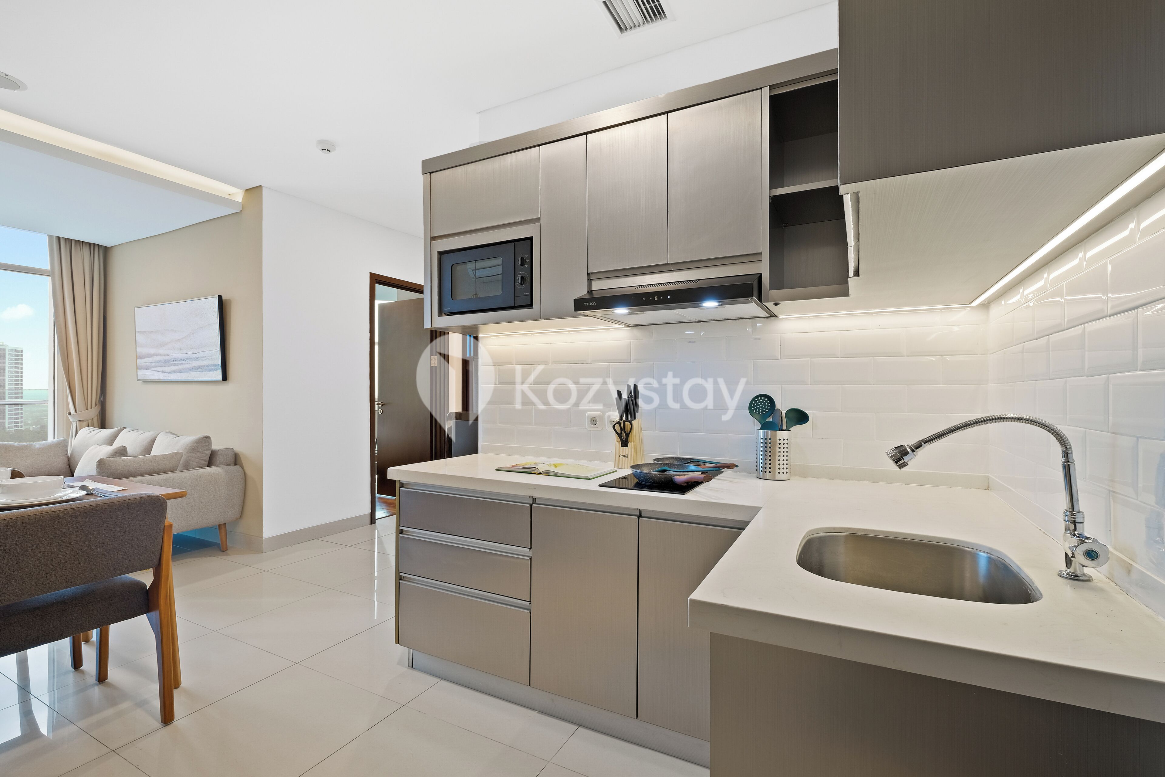 A modern kitchen with a built-in microwave, stainless steel sink, and a dining area with a table and chairs.