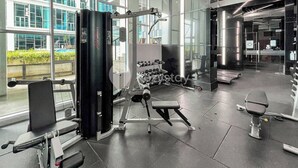 Ein modernes Fitnessstudio mit unterschiedlichen Trainingsgeräten, großen Fenstern und Blick ins Freie.