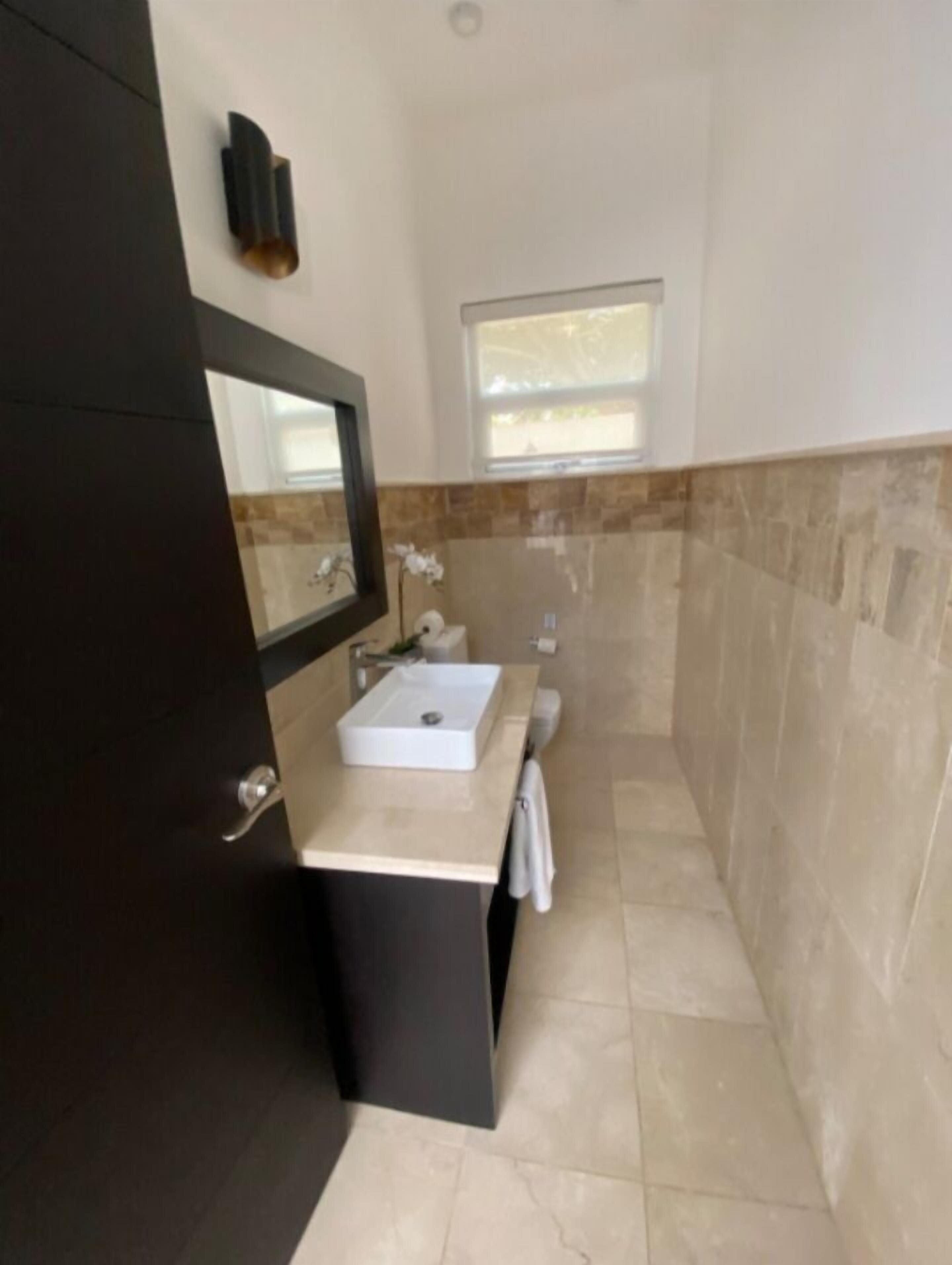 A modern bathroom with a dark-toned vanity, a white sink, and a mirror.