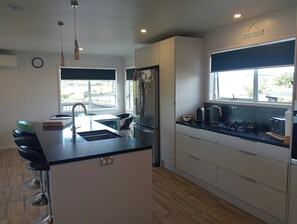 A modern kitchen with a central island, a built-in oven, and a window overlooking a balcony.