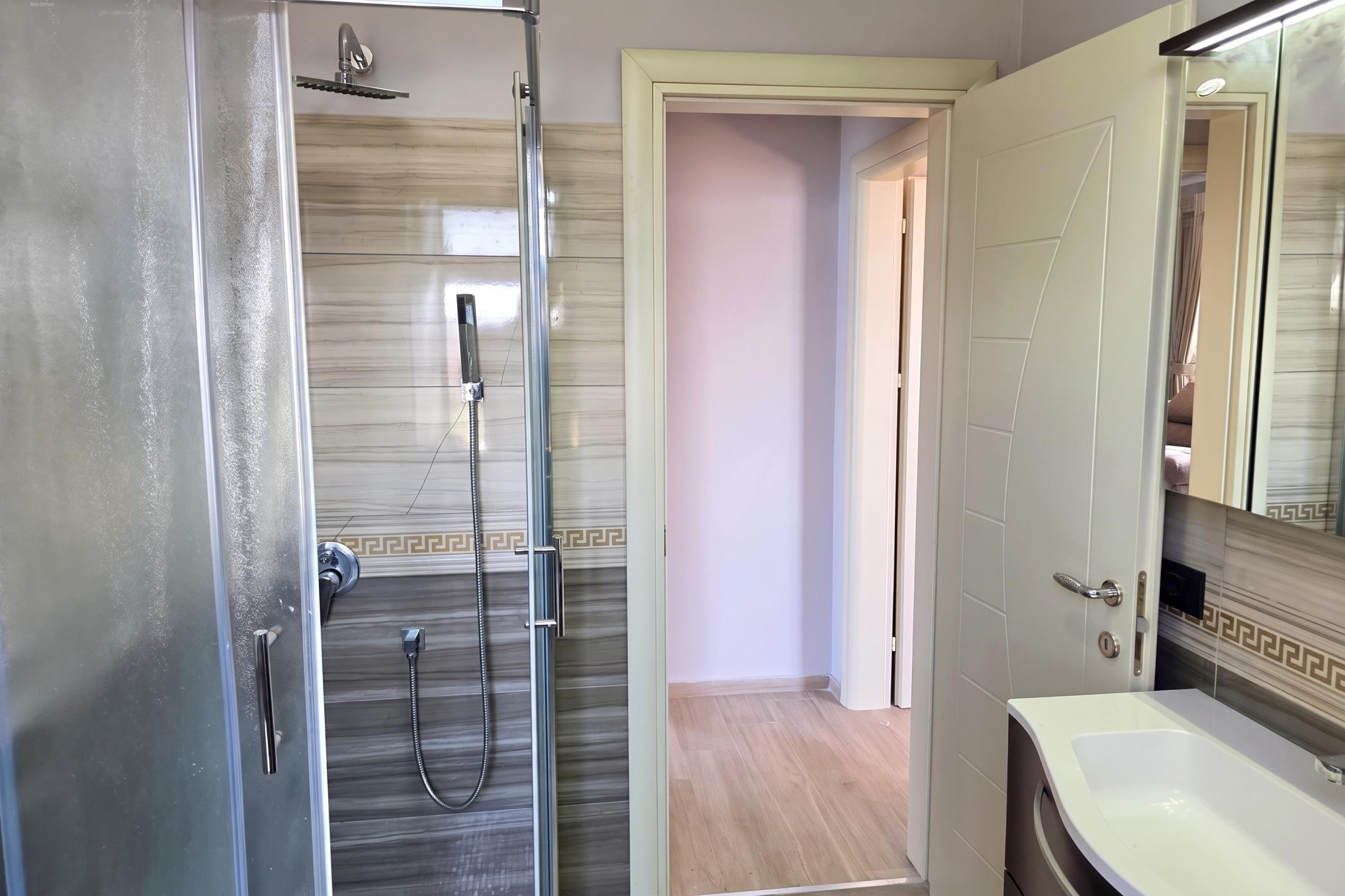 Ein Badezimmer mit Dusche, Waschbecken und Spiegel.