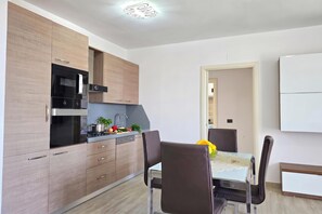 A modern kitchen with built-in appliances, a dining area with a table and chairs, and a whiteboard on the wall. - Sea Vista Durres 50m from beach, Durres, Albania (Durres)