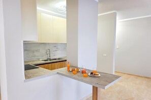 Une cuisine moderne dotée d’un plan de travail en marbre, d’un évier encastré et d’un coin petit-déjeuner avec du jus d’orange et des viennoiseries.