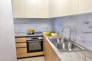 A modern kitchen with a built-in oven, a sink, and a wooden countertop. - Sea View Apartment in Durres Beach 100, Durres, Albania (Durres)
