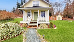 A two-story house with a front porch, a small attached garage, and a well-maintained lawn. - Cozy Cottage w/ Hot Tub in Freeland, Pets Welcome! (Freeland)