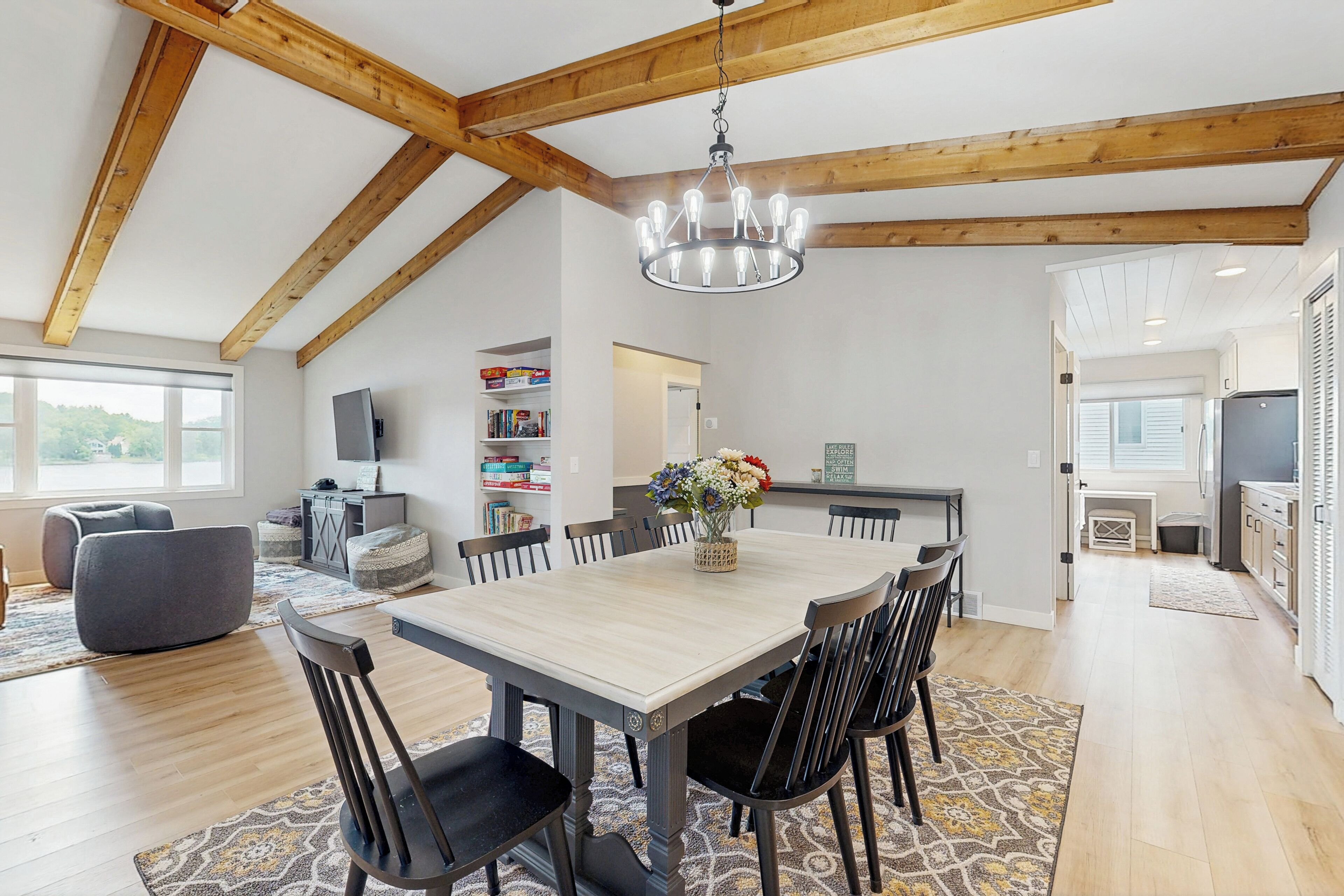Une salle à manger spacieuse avec un plafond en bois, un lustre et une grande table entourée de chaises.