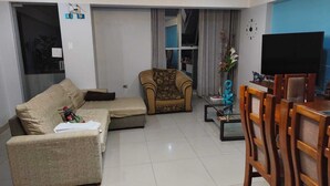 Sala de estar com sofá, poltrona e televisão.