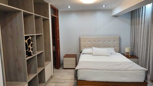 Quarto com cama, guarda-roupa e mesa de cabeceira.