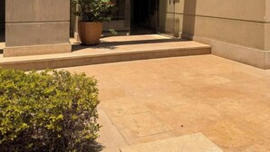 A modern building entrance with a number '5' sign, a potted plant, and a small bench.