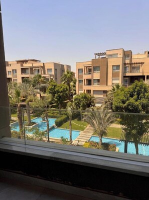 A view of a residential building complex with multiple apartment buildings, a swimming pool, and surrounding greenery.
