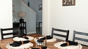 A dining area with a wooden table, black chairs, and a hanging light fixture. - Sleeps 12 - Pool, Hot Tub & Game Room (Grand Prairie)
