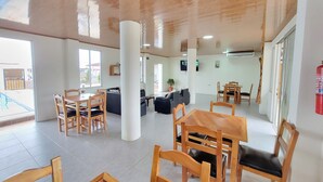 A spacious indoor area with wooden furniture, a large pillar, and a fire extinguisher on the wall. - Dalai Beach Stay  (Salango)