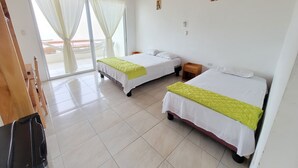 A hotel room with two beds, a wooden desk, a small wooden nightstand, and a sliding glass door leading to a balcony. - Dalai Beach Stay  (Salango)