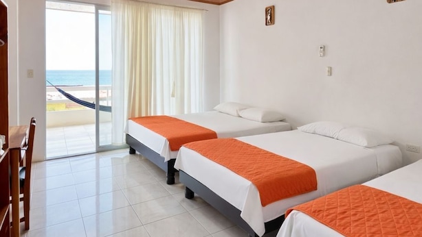 A hotel room with three beds, a wooden ceiling, a view of the sea, and a balcony. - Dalai Beach Stay  (Salango)
