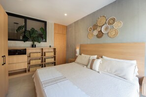 A modern bedroom with a large bed, wooden headboard, and a wall-mounted mirror. There are storage units with baskets and a potted plant. - Best of BOTH Worlds!  Close to Santa Cruz but Quiet!! (Bahia Santa Cruz)