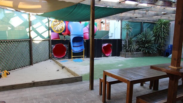 Un espace extérieur abrité comprenant un toboggan, une table et un banc.