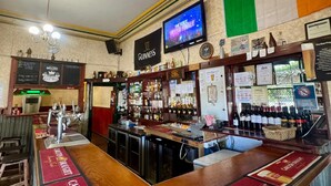 A bar with a Guinness sign, a television displaying 'The Voice', and a menu board. - Royal Exchange Hotel Burra (Burra)