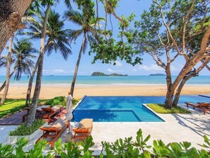 A poolside area with lounge chairs and a view of the beach. - the nest private beach resort (Chumphon)