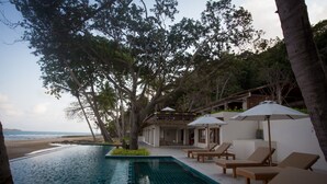 A pool area with lounge chairs and umbrellas, overlooking a beach. - the nest private beach resort (Chumphon)
