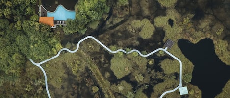 An aerial view of a park with a winding path, a blue building, and a small pond.