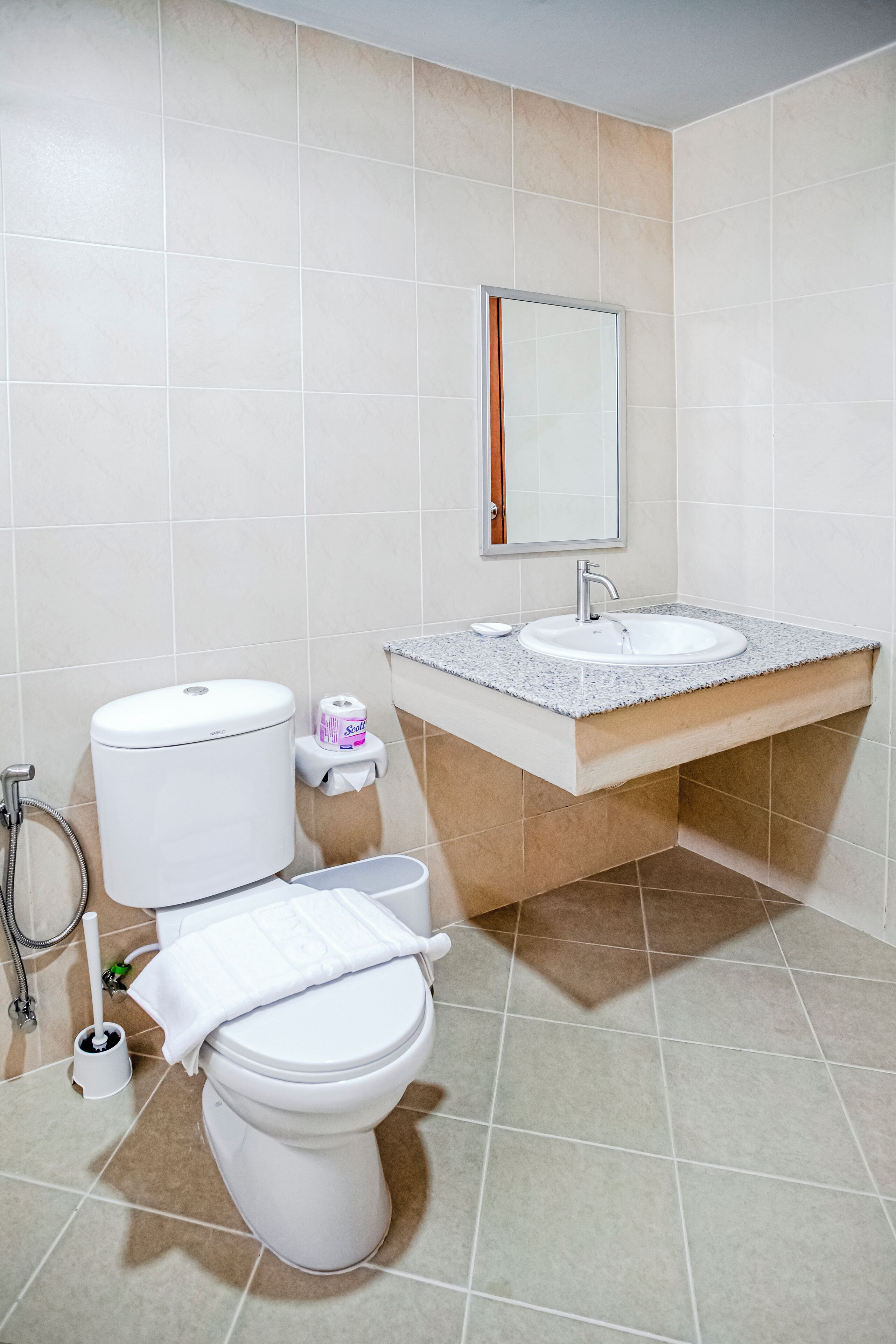 A bathroom with a toilet, sink, and mirror.
