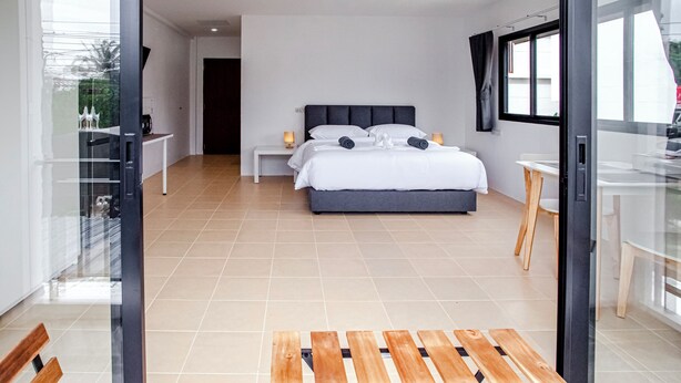 Ein modernes Schlafzimmer mit einem großen Bett, Nachttischen und einer Glast ür, die auf einen Balkon führt.