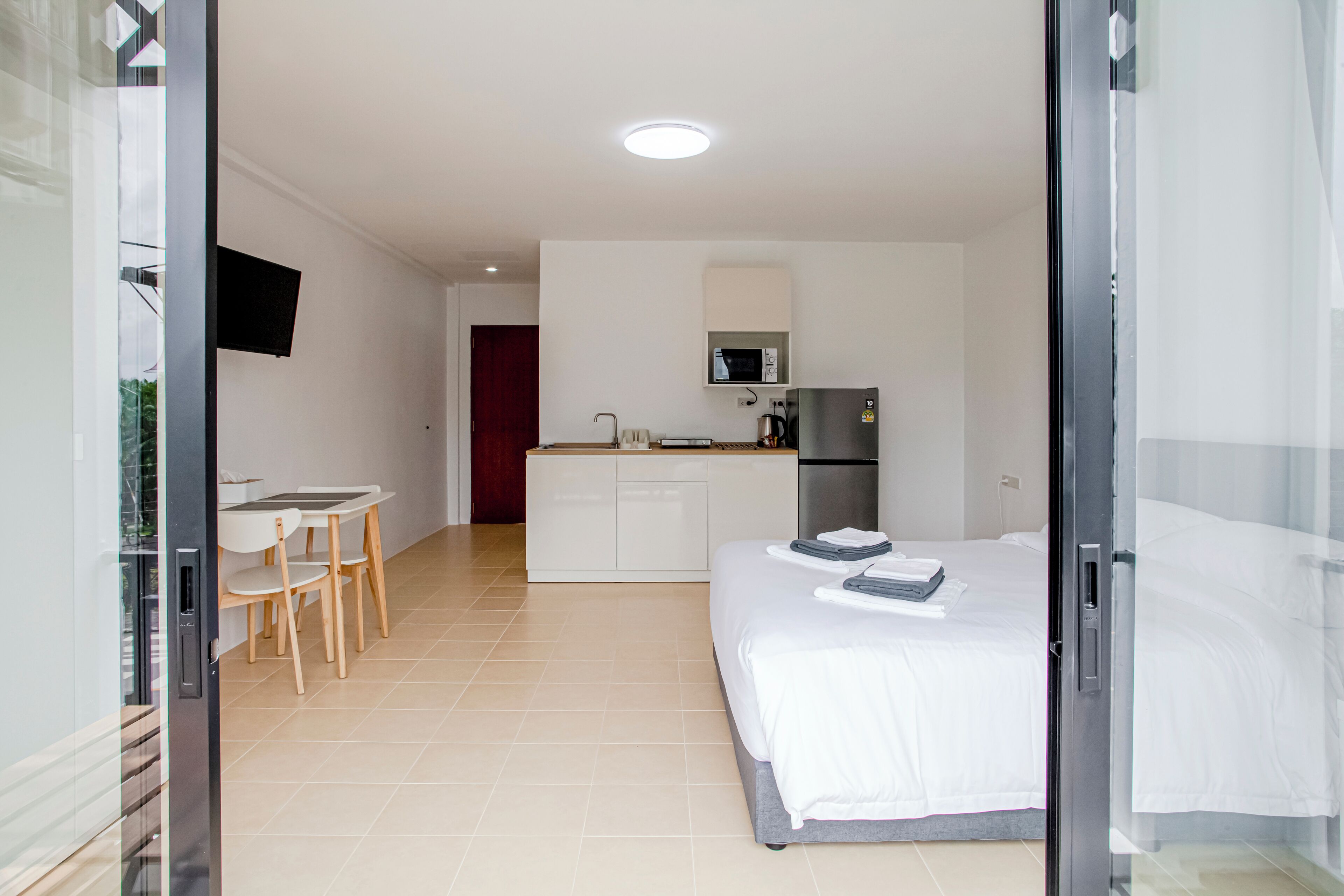 Une chambre d’hôtel comprenant un lit, une petite kitchenette, un coin repas avec une table et des chaises, et un téléviseur fixé au mur.