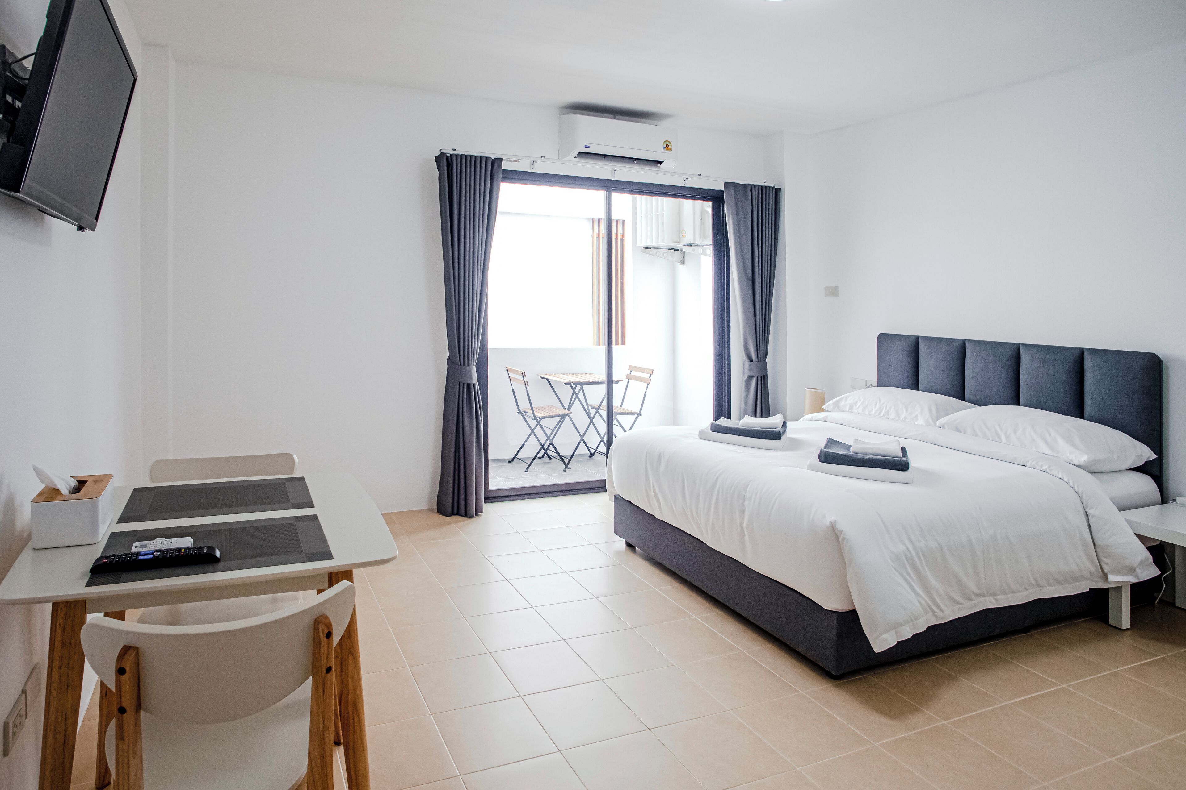 A modern hotel room with a bed, a desk, and a chair.