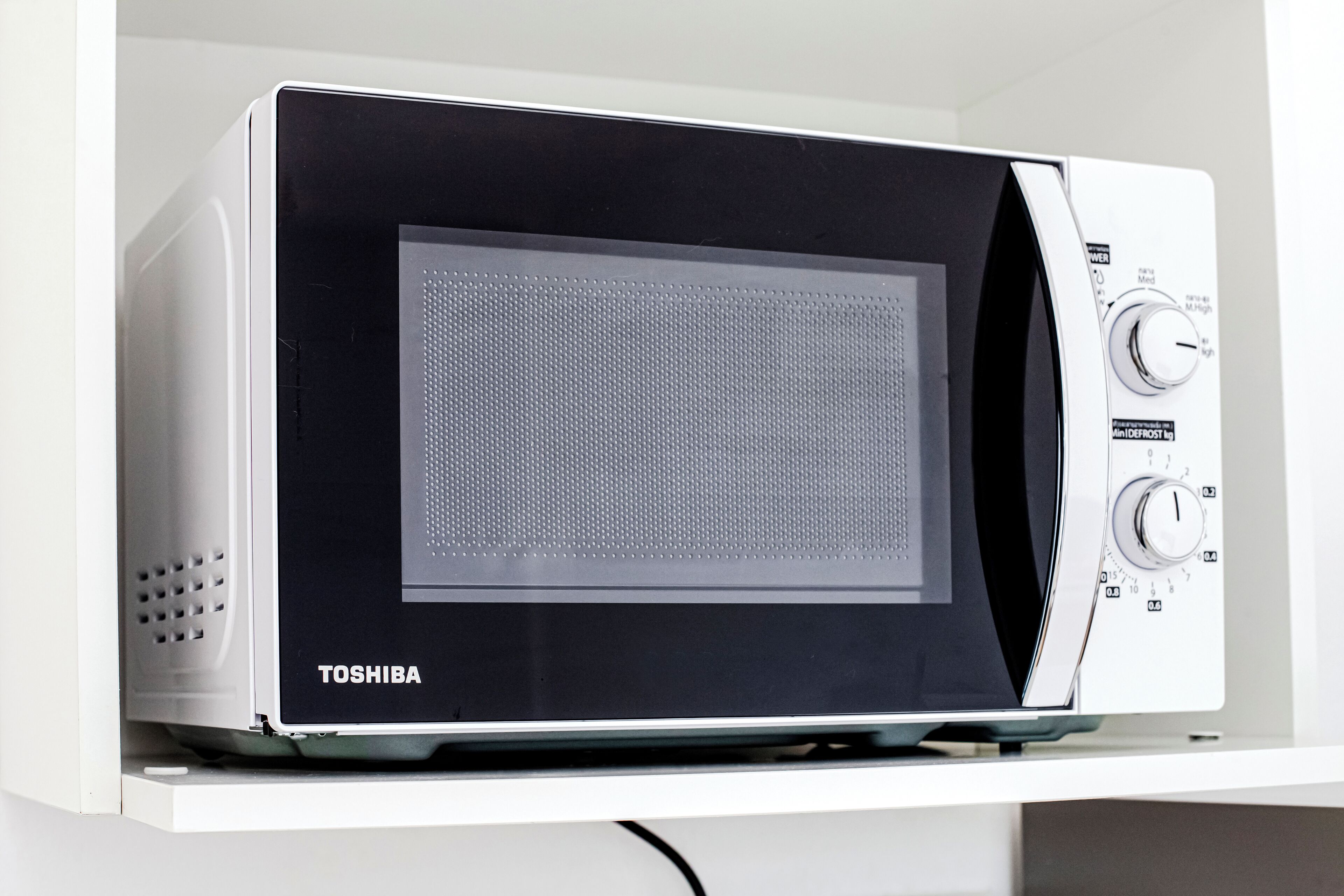 Un microondas blanco con pantalla digital y perillas de control.