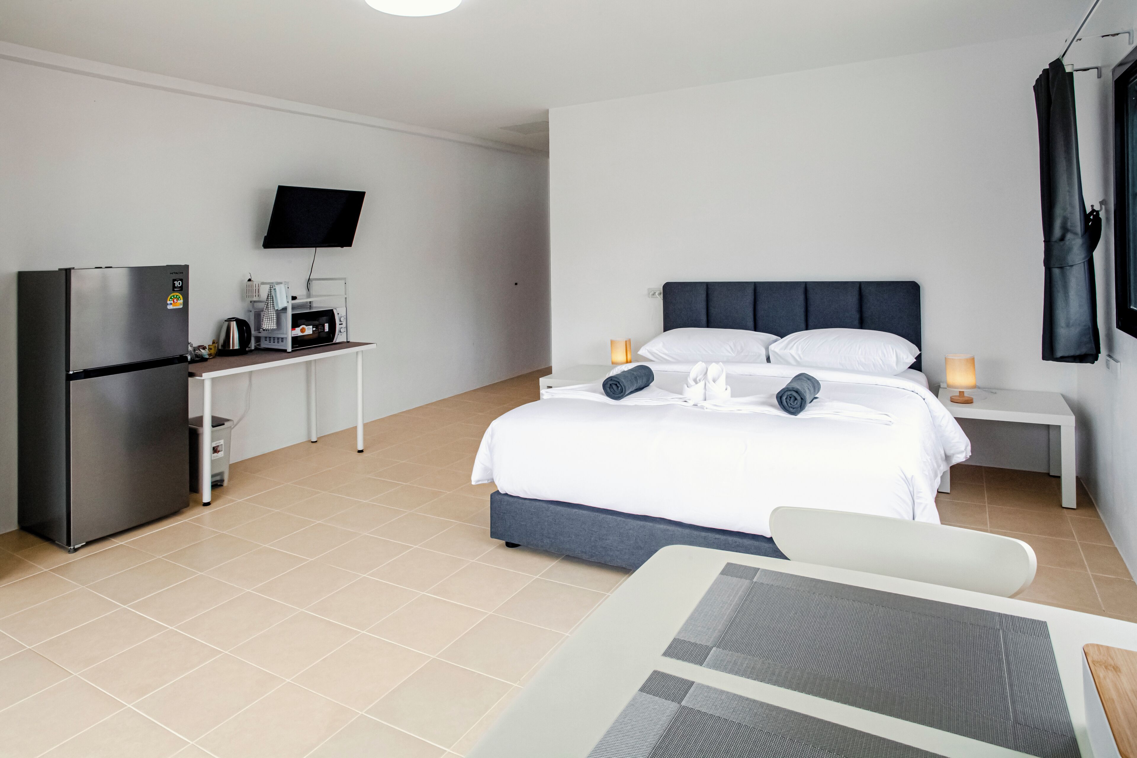 Une chambre d’hôtel moderne équipée d’un lit, d’un bureau avec un réfrigérateur, un four à micro-ondes et un téléviseur à écran plat.
