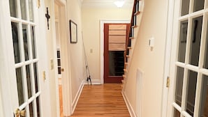 A hallway with wooden flooring, white doors with glass panels, and a staircase leading to another level. - Elk River Retreat, in Rogersville AL (Rogersville)