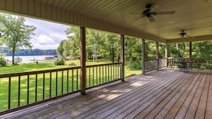 A wooden deck with a railing, a ceiling fan, and a view of a lake and trees. - Elk River Retreat, in Rogersville AL (Rogersville)