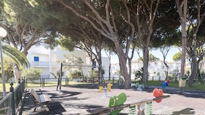 Un parque infantil con columpios, un sube y baja y un banco.