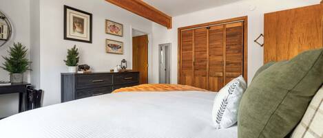 A bedroom with a bed, wooden wardrobe, and a ceiling fan.