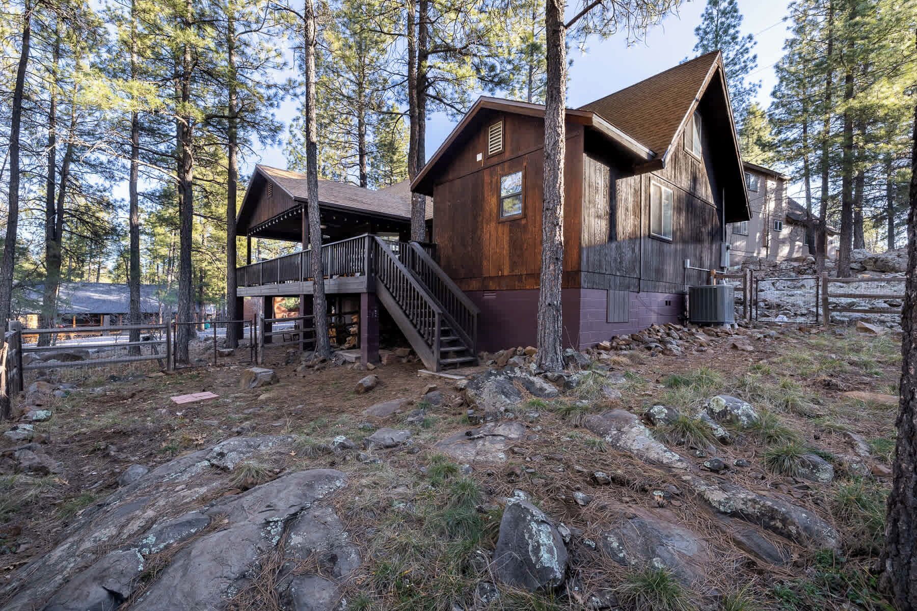 A rustic cabin with a wooden exterior, a covered porch, and a staircase leading to an upper level.
