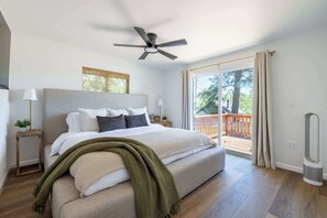 Ein Schlafzimmer mit Bett, Deckenventilator, Fenster und Blick auf eine Terrasse.