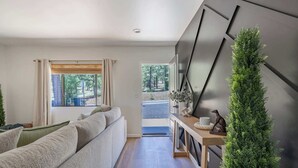 Ein modernes Wohnzimmer mit einer Couch, einem kleinen Tisch mit Dekoration und Blick ins Freie.