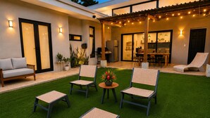 Eine Terrasse mit vier Stühlen, einem Tisch und einem Grillbereich.