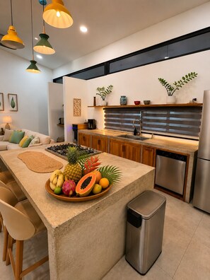 A modern kitchen with a central island, stainless steel appliances, and a variety of fruits. - 3-bedroom house with private pool, AC, fitness center-5min from the sand. (Provincia de Guanacaste)
