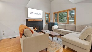 A living room with a fireplace, a sofa, a coffee table, and a TV mounted on the wall. - Homestead Hideaway - Amenities, Mins from Skiing (Edwards)