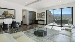 A modern living room with a glass coffee table, a sofa, and a dining area with chairs. - Juniper Ridge at Cordillera Valley Club (Edwards)