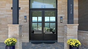 A building entrance with a double door, stone walls, and two potted yellow flowers. - Juniper Ridge at Cordillera Valley Club (Edwards)