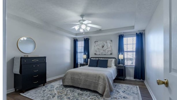 A bedroom with a bed, a dresser, a ceiling fan, and a window with curtains. - Quiet 3BR Duplex • Ideal for Travel, Long-Term Stays, Nurses, & Military Guests (Elizabethtown)